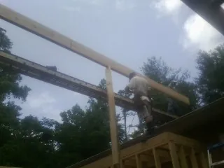 Carpenter setting a ridge beam over a new addition frame — Ice Dam Removal by Roofing Brothers in Boyden