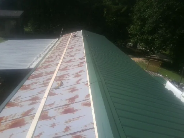 Old rusted panels beside newly installed green metal roofing — Wind Damage Roof Repair by Roofing Brothers in Boyden