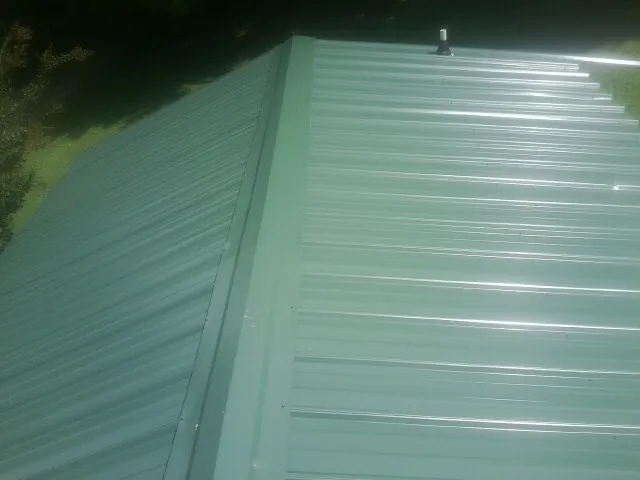 New green metal panels meeting at the ridge of a roof — Flat Roof Repair work by our crew in Boyden