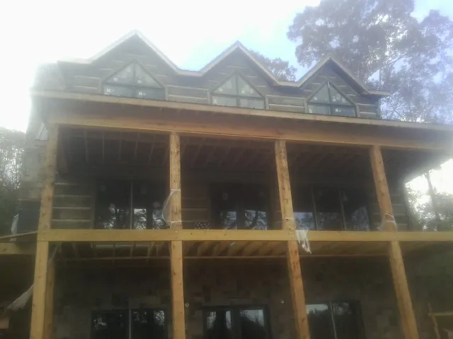 Dormers and porch framing on a large log home under construction — Roof Coating work by our crew in Boyden