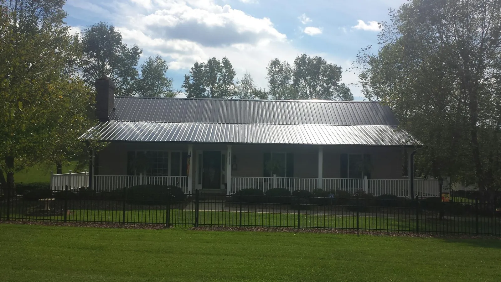 Gray metal roof on a brick ranch with a full width front porch — Gutter Guard Installation work by our crew in Boyden