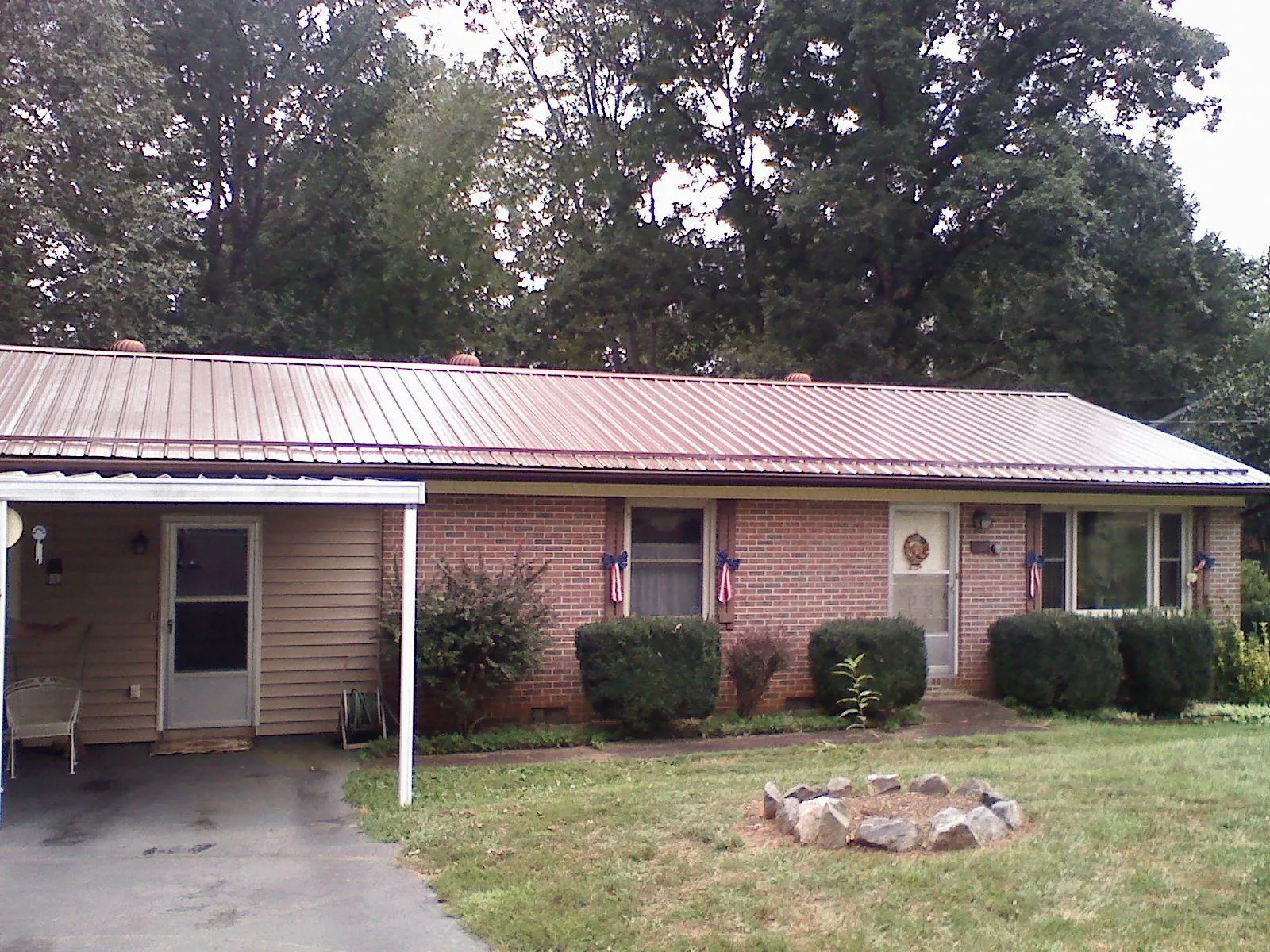 Bronze metal roof and carport on a brick ranch home — Roof Repair work by our crew in Boyden