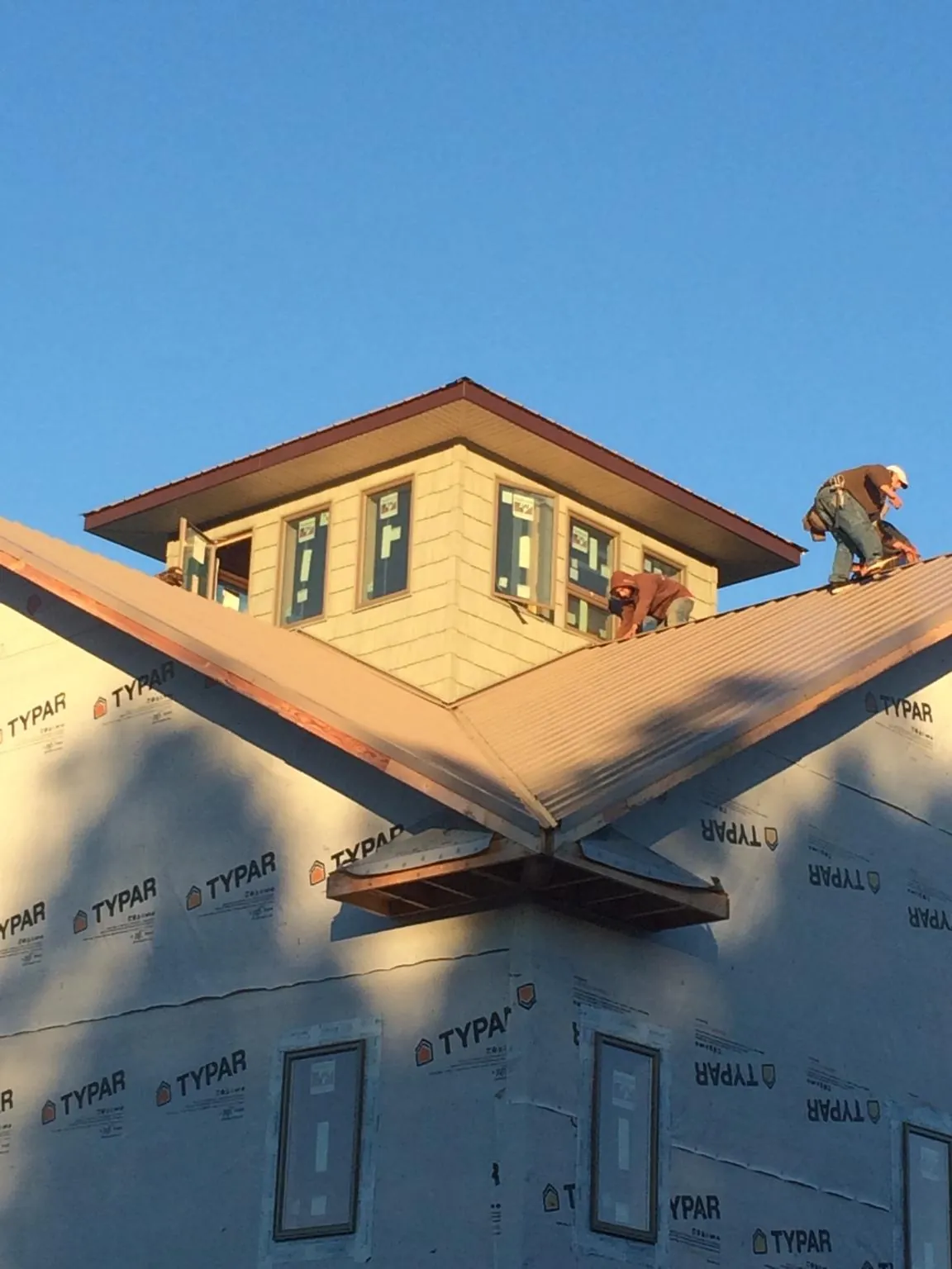 Roofers working around a rooftop cupola on a new metal roof at sunset — Roof Waterproofing in Boyden by Roofing Brothers